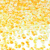 A close-up of bright yellow and orange sea shell PVC sequins scattered on a white background for nail art and craft decoratio