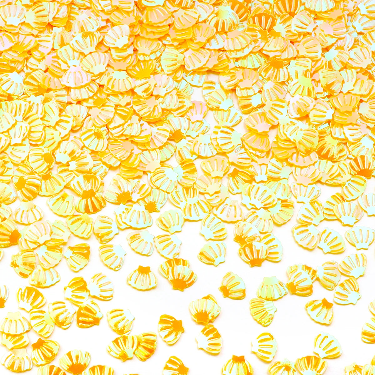 A close-up of bright yellow and orange sea shell PVC sequins scattered on a white background for nail art and craft decoratio