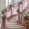 A grand staircase decorated with pink tulle draping and floral arrangements for an elegant event backdrop.