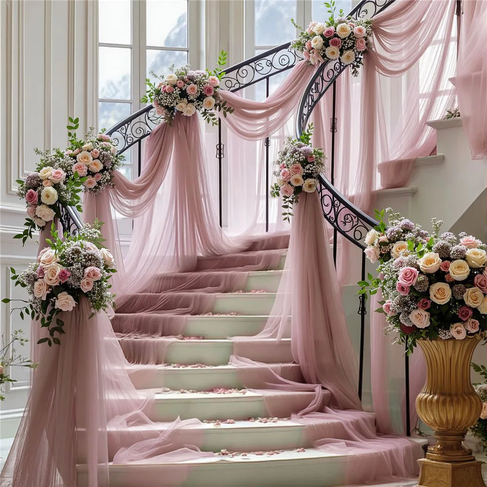 A grand staircase decorated with pink tulle draping and floral arrangements for an elegant event backdrop.