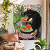 A tapestry featuring a black cat sitting in a glass bowl filled with goldfish and green foliage.