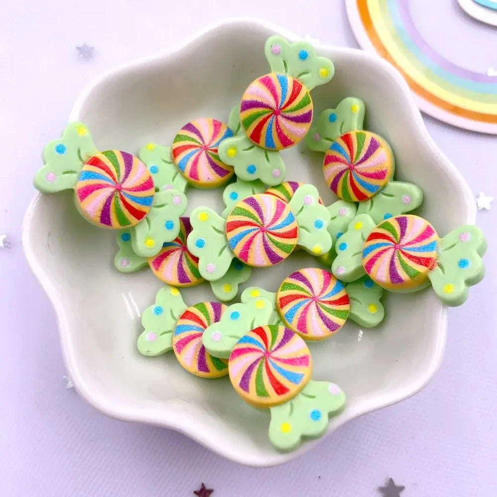 A white dish holds numerous colorful, striped candy resin cabochons in pink, green, and yellow hues.