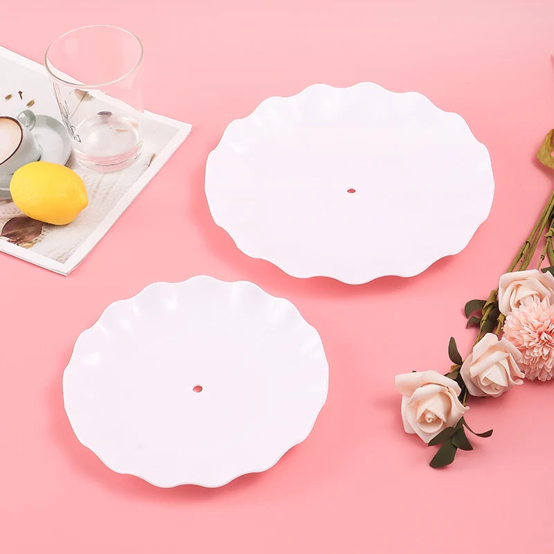 White ceramic serving plates and a glass on a pink surface with a lemon and roses.