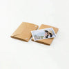 A brown accordion folding photo album with a photo inside showing a woman's profile.
