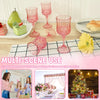 A set of elegant pink plastic wine glasses displayed on a checkered mat with festive holiday decorations.
