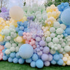 A vibrant wall display of pastel rainbow latex balloons in various shades of pink, blue, yellow, and green.