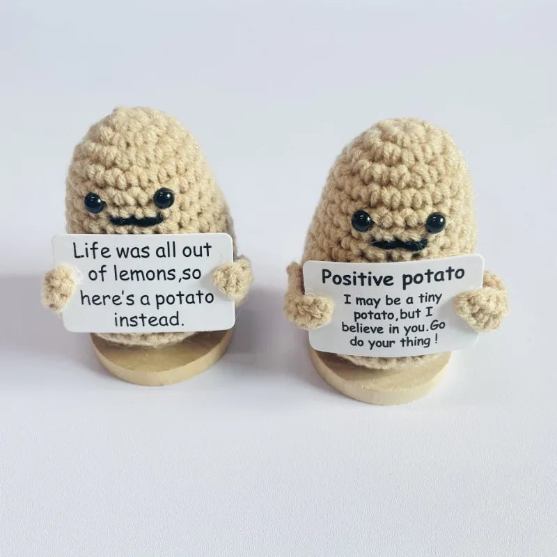 Two handmade knitted plush dolls shaped like potatoes with signs encouraging a positive outlook