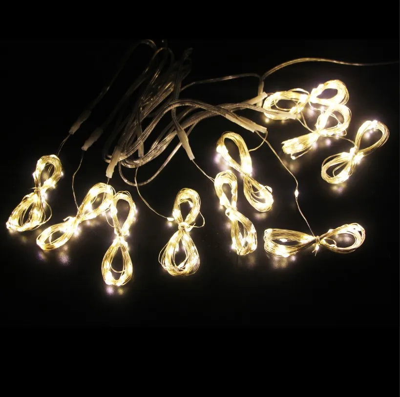 String of warm white LED curtain fairy lights with small bulbs and wires against a dark background