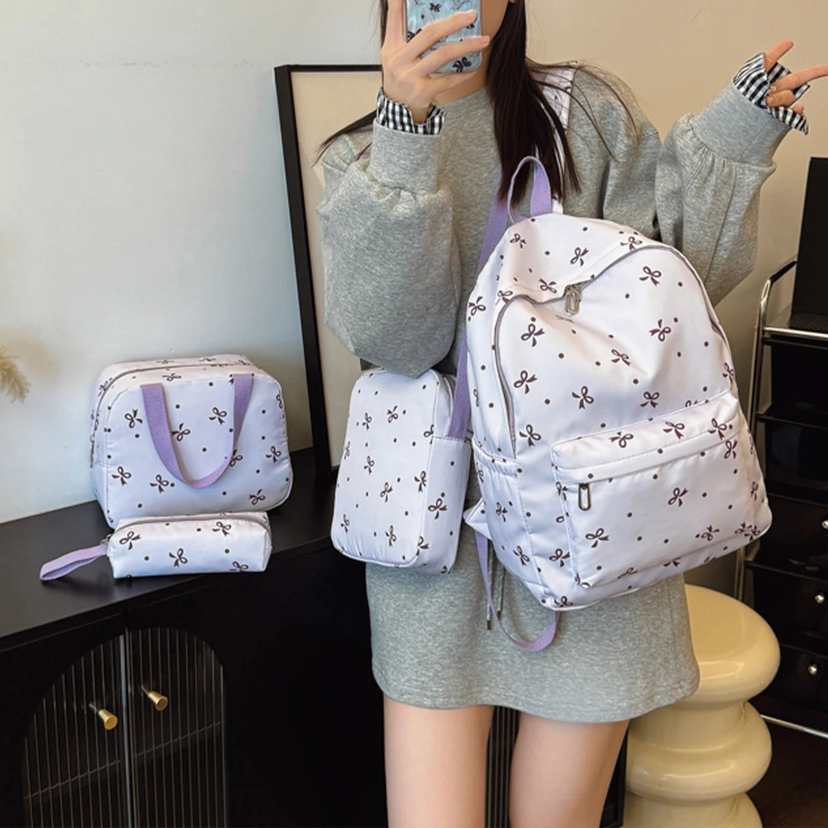 A woman holds a white backpack set featuring a bow print and matching accessories.