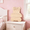 Panneau d'affichage de photos commémoratives en forme d'ours en bois, posé sur une commode blanche.