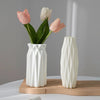 Moderne weiße Plastikvase hält rosa und weiße Tulpen auf einem Holztablett.