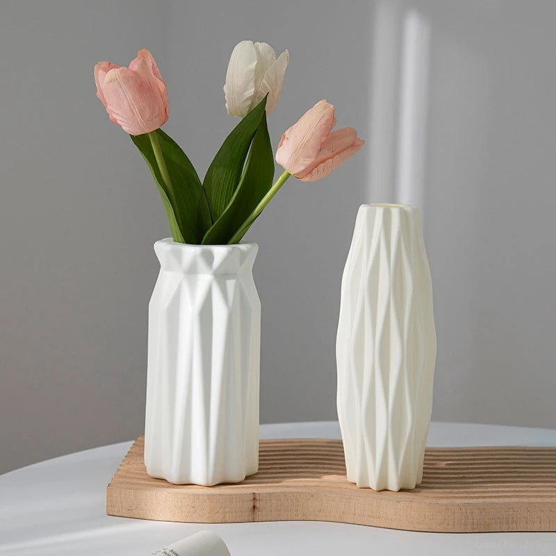 Moderne weiße Plastikvase hält rosa und weiße Tulpen auf einem Holztablett.