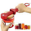 A hand is using a red ergonomic jar and bottle opener set to open a glass jar.
