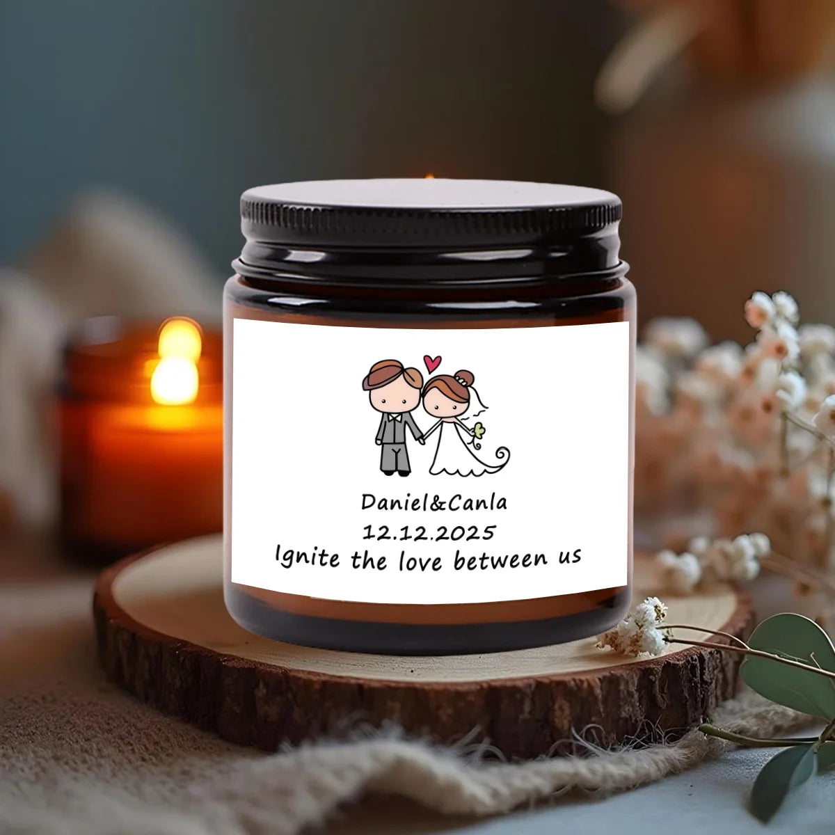A glass jar candle with a label featuring the names Daniel & Canla and the date 12.12.2025
