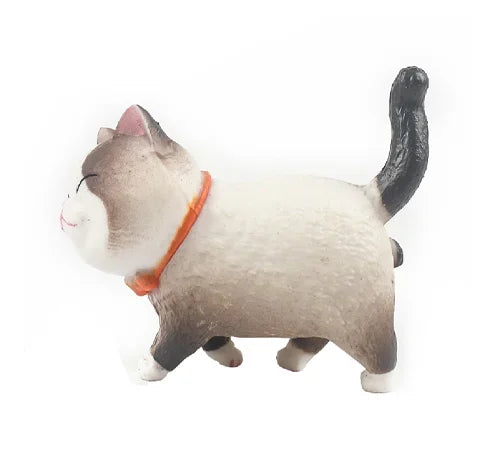 A small, gray and white 3D cartoon cat figure with an orange collar.