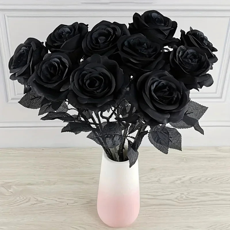 A bouquet of artificial black roses in a white vase on a light wooden surface.