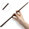 A hand holds a dark brown metal-resin magic wand with a textured grip, demonstrating its size and shape.