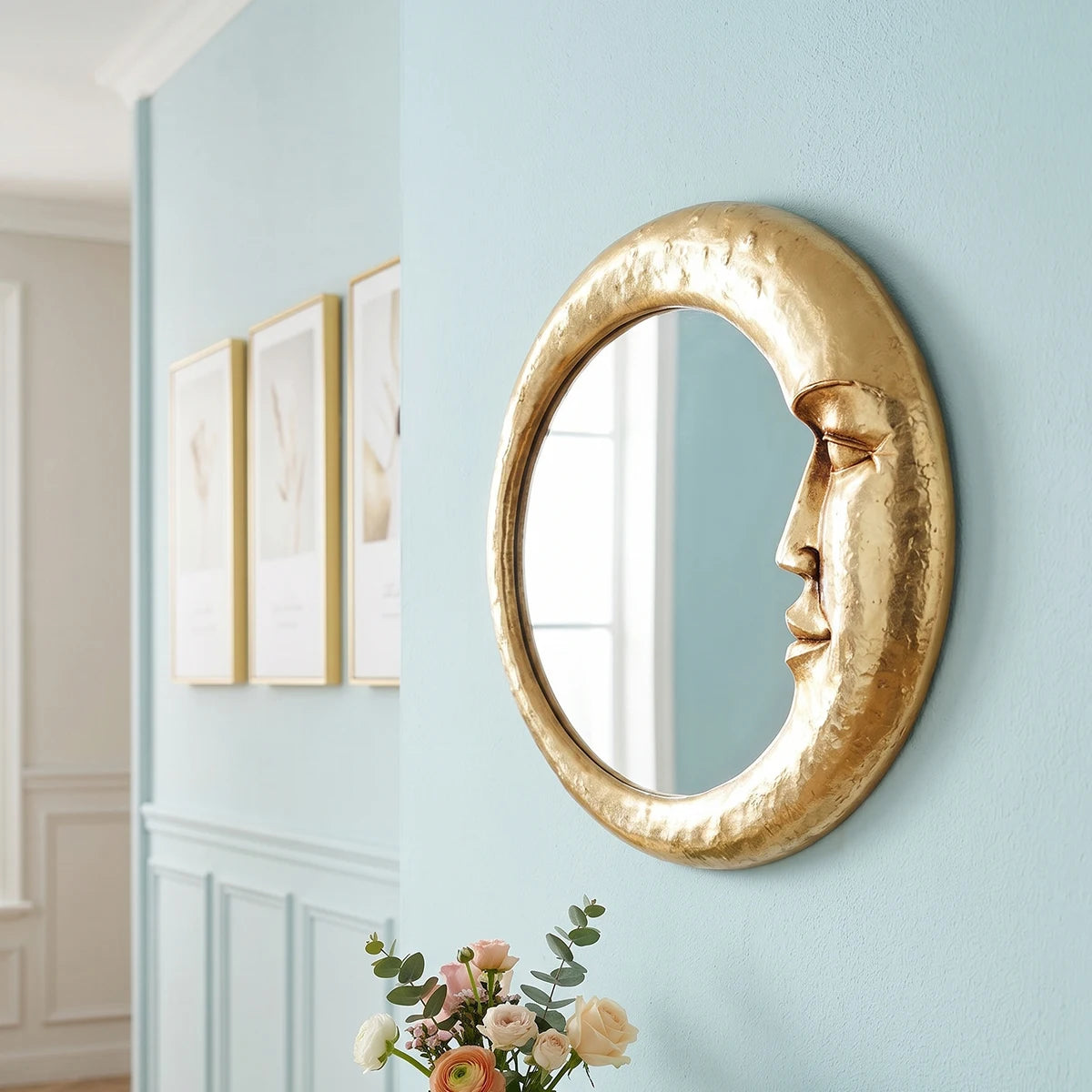 A round, golden crescent decorative wall mirror mounted on a light blue wall.