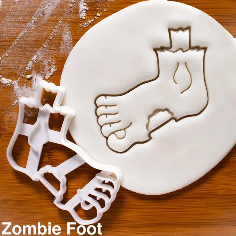 A white fondant cookie cutter shaped like a zombie foot is placed on a wooden surface.
