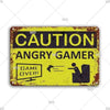 A vintage metal sign with a distressed yellow background and black text warning about an angry gamer and game over.