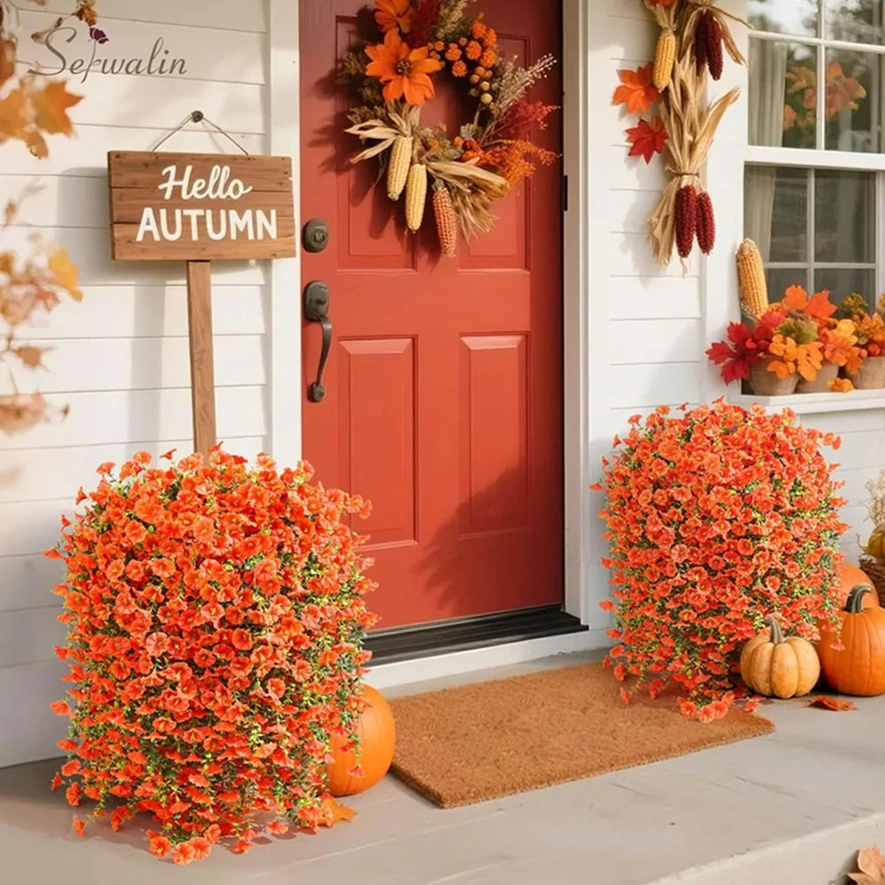 An artificial morning glory vine in bright orange and white blooms decorates the entrance of a red door.
