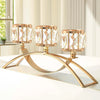 A three-arm gold crystal candelabra with faceted glass candle holders resting on a white surface.