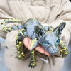 A hand holds a realistic Sphynx cat fidget toy with gray and yellow skin texture.