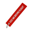 Red woven tag with the text Kiss Me Before Flight attached to a metal keychain.