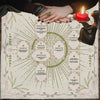 A hand holds a Celtic Cross altar cloth featuring a tarot design and a lit red candle.