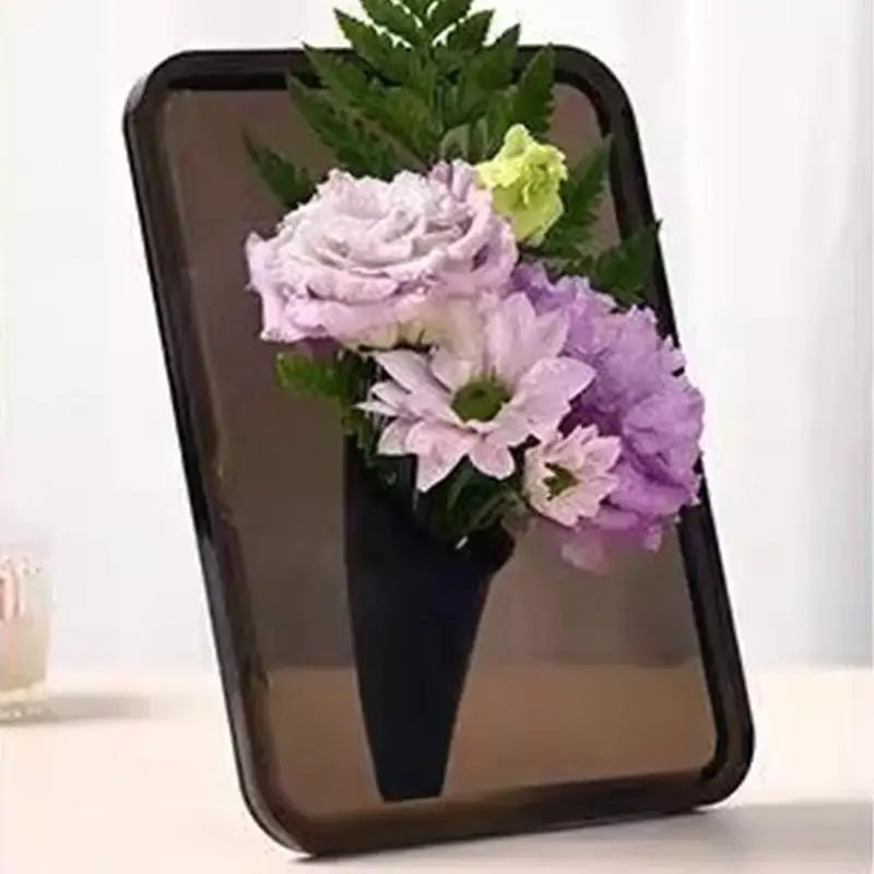 A clear acrylic frame holds a potted purple and pink floral arrangement.