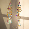 A hanging crystal suncatcher wind chime ornament featuring purple and gold elements.
