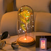 An LED galaxy rose artificial flower displayed inside a glass dome on a wooden base.