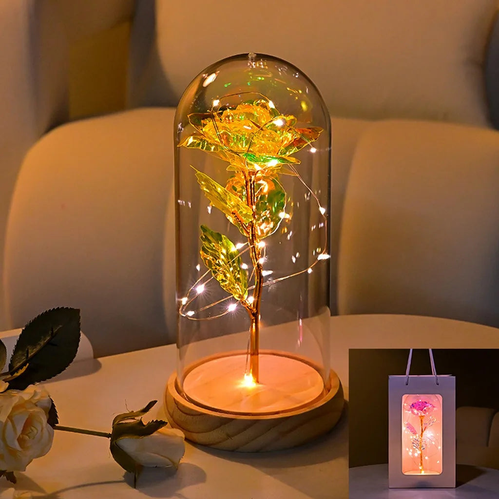 An LED galaxy rose artificial flower displayed inside a glass dome on a wooden base.