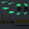 A wall display featuring glowing green dinosaur silhouettes on a gray wall above a sofa and decorative vases.