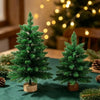 Mini tabletop LED Christmas tree with warm glow decorated on a green surface.