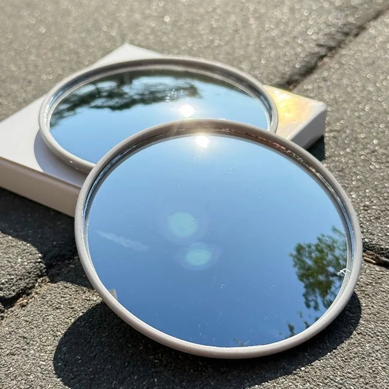 Runder tragbarer konvexer Selfie-Spiegel, der die Umgebung auf einer grauen Außenfläche reflektiert.