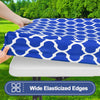 A blue patterned waterproof elastic fitted tablecloth is being placed on a white table.
