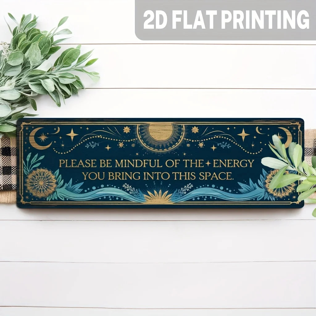 A rectangular dark blue metal tin sign featuring celestial designs and text on a white wooden surface.