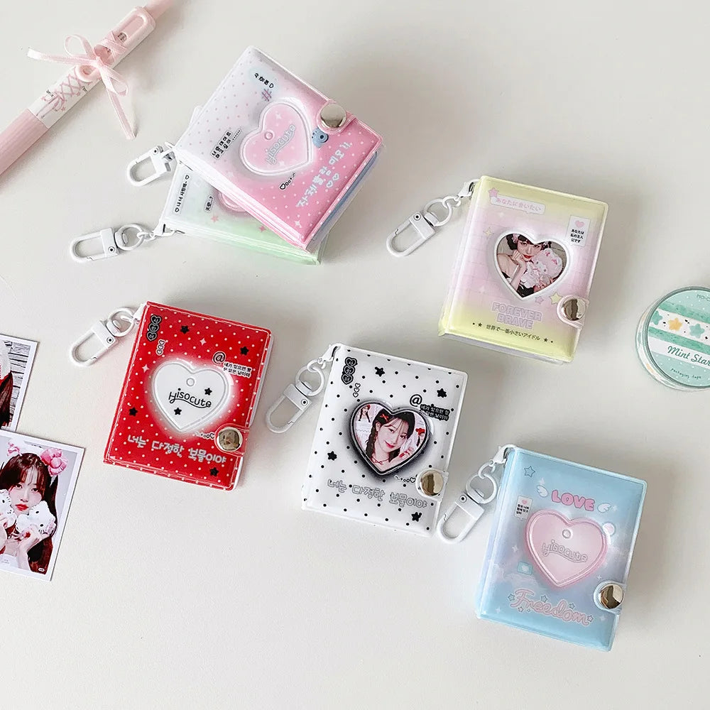 A collection of pink and clear heart-shaped photo album keychains and accessories arranged on a white surface.