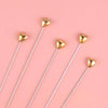 A set of gold heart-shaped cake toppers on white sticks for birthday parties
