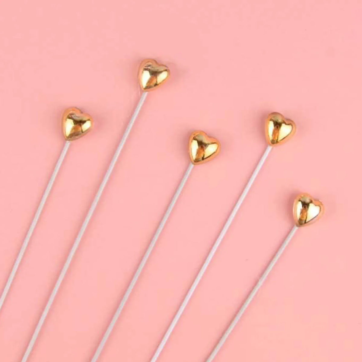 A set of gold heart-shaped cake toppers on white sticks for birthday parties