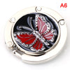 A silver foldable handbag hook with a black and red butterfly design.