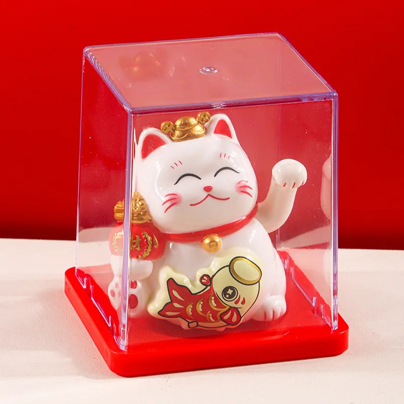 A white lucky cat figurine with a gold crown and red collar is displayed inside a clear red box.