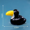 Petite sculpture en résine noire d'un oiseau à bec jaune, sur fond bleu.