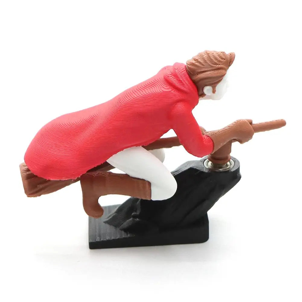 A figurine of a witch and wizard riding a flying carriage, featuring a red coat and white hair.