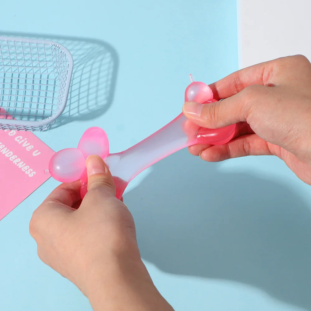 A hand is squeezing a pink squishy stress relief toy shaped like a dachshund.