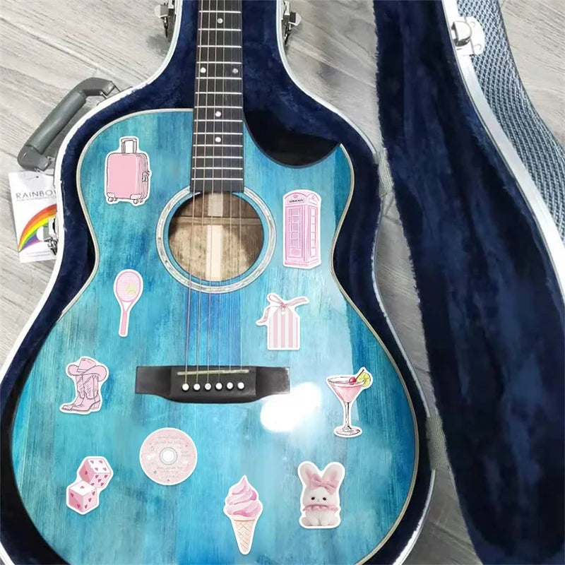 A blue acoustic guitar decorated with various pink cartoon PVC stickers and accessories.