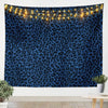 A dark blue leopard print tapestry wall hanging illuminated by warm string lights.