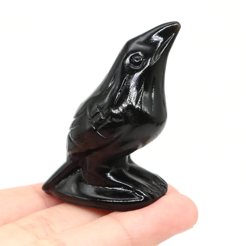 Hand-carved black obsidian raven figurine resting on a hand