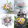 A bouquet of mixed pink purple and yellow flowers wrapped in gold edge floral wrapping paper